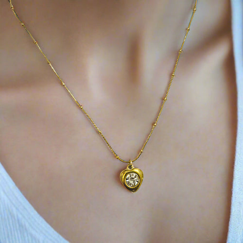 Gold necklace with a heart-shaped pendant on a mannequin